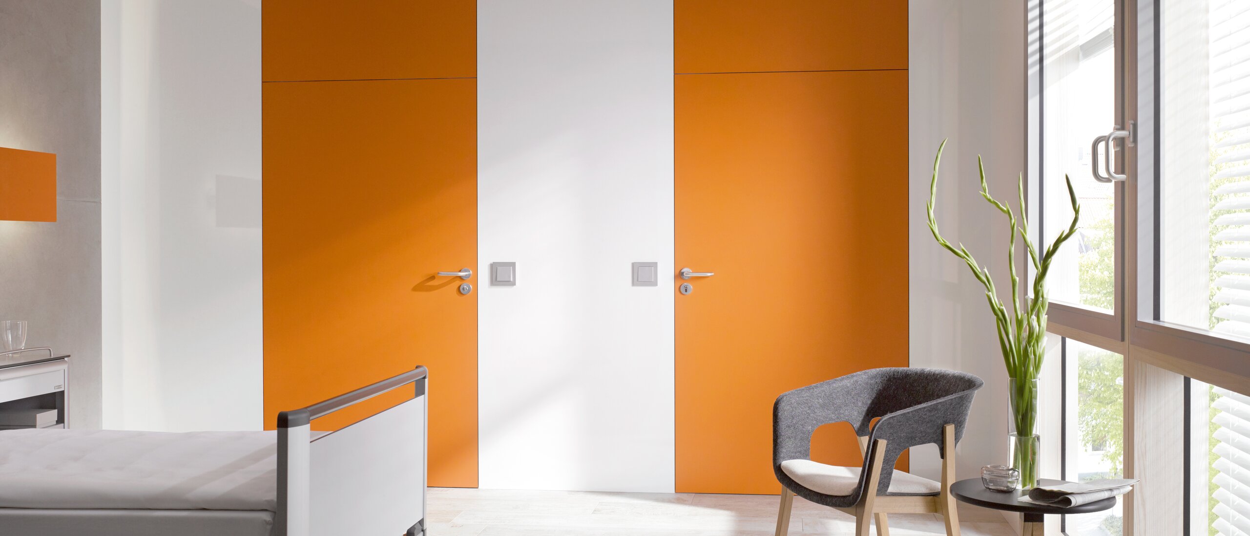 HEWI lever handle 111 White hospital room with two orange doors fitted with a lever handle in the colour grey made of polyamide