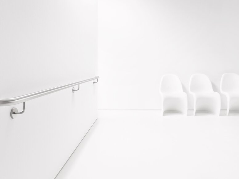 ENTRO stainless steel handrail Stainless steel handrail attached to a white wall with three supports